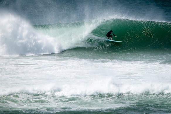 People surf at Dixon Park Beach on Friday ahead of massive swells expected.