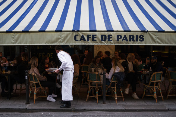 A waiter serves customers eating and drinking on the terrace area outside Cafe de Paris in September, ahead of the enforcement of new COVID-19 restrictions in Paris.