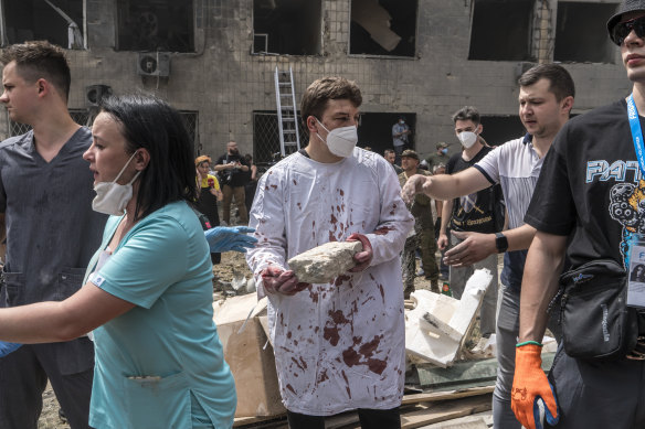 Dr Ihor Kolodka, covered in his own blood, helps others clear rubble after a Russian missile strike on the Ohmatdyt children’s hospital.