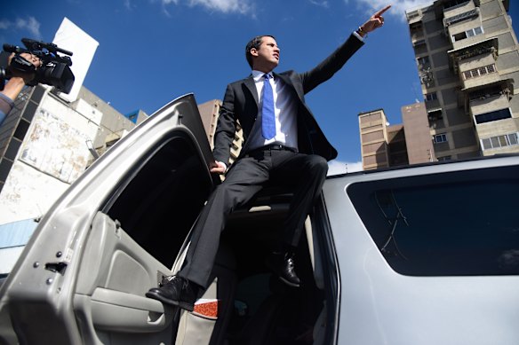 Guaido stands on a car and points to buses arriving with his supporters on board.
