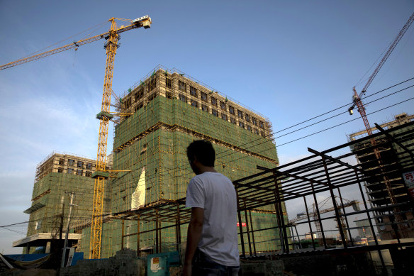 A pedestrian walks past a construction site in Sihanoukville, Cambodia, where an infusion of Chinese-built infrastructure promises to pay off with jobs and prosperity. 