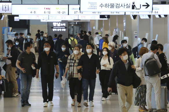 People wearing face masks arrive at the domestic flight terminal of Gimpo airport in Seoul.