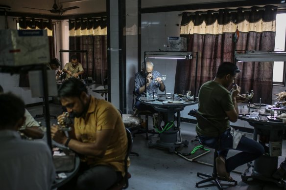 Employees inspect and polish diamonds at a workshop in Surat, Gujarat.