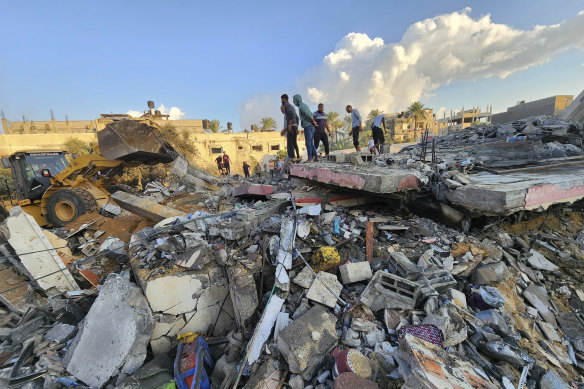 Palestinians stand by the rubble of a building destroyed in Israeli airstrikes in Deir el-Balah Gaza Strip on Sunday.