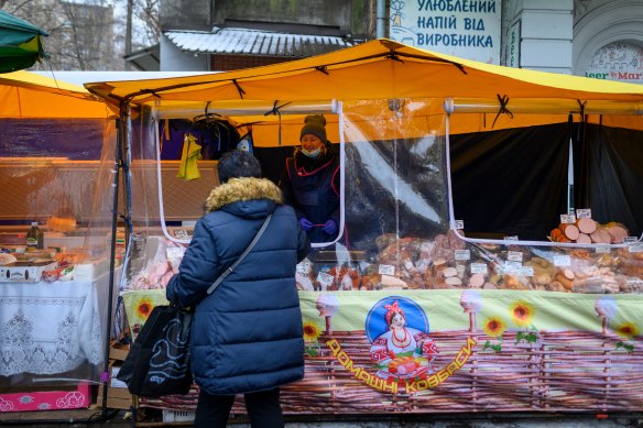 A customer shops at a cooked meats stall at a weekly farmers market outside the Klovska Metro station in Kyiv on Friday.