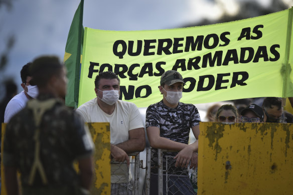 Demonstrators stand with a banner that reads in Portuguese, "We want the armed forces in power," at the Alvorada palace, after a protest demanding military intervention during the new coronavirus emergency in Brasilia.