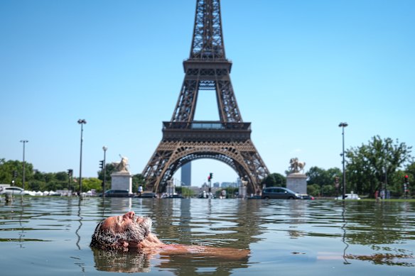 Un uomo si rinfresca nella Fontana di Varsavia nei Jardins du Trocadéro di fronte alla Torre Eiffel a Parigi.