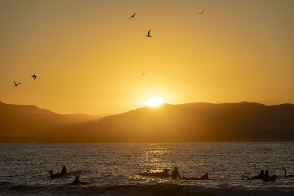 Surfers enjoying the sunset in Byron Bay before the forecast weather change.