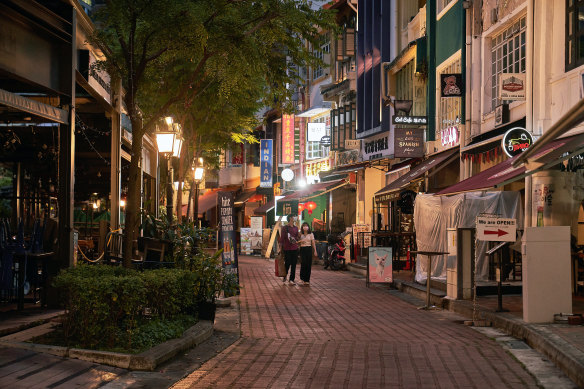 Pedestrians walk along a deserted street in the Boat Quay area of Singapore.