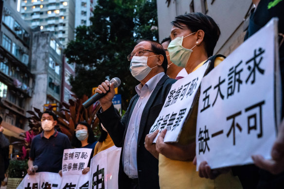 Pro-democracy supporters hold banners and shout slogans outside of the  Western District police station in Hong Kong after at least 14 pro-democracy veterans and supporters were arrested on Saturday.