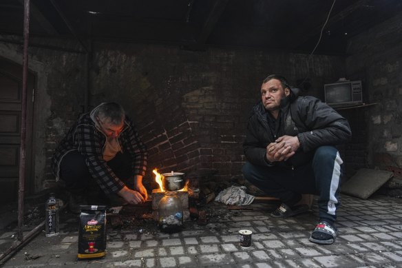 Men cook a meal in a yard in Mariupol, Ukraine, Sunday, March 6, 2022.