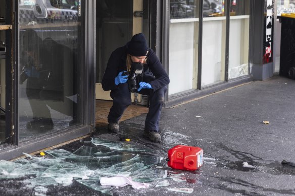 An investigator photographs evidence at the scene of a suspicious fire in Collingwood on Thursday morning.