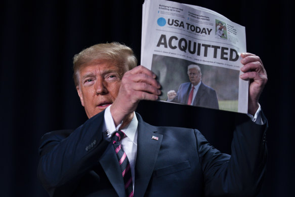 Donald Trump holds up a newspaper following his acquittal in the Senate.