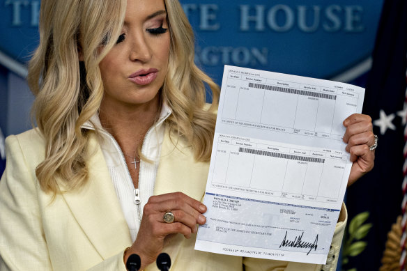 Kayleigh McEnany, White House press secretary, holds a cheque in the amount of US President Donald Trump's annual quarterly salary, to be donated to the US Department of Health and Human Services.