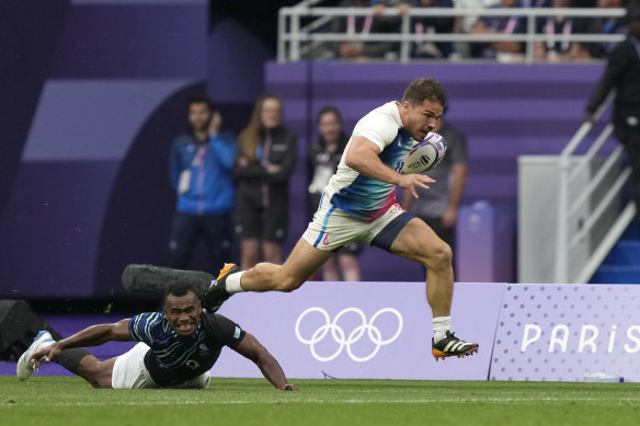 Antoine Dupont of France races clear of Fiji’s Waisea Nacuqu to score a try during the men’s gold medal Rugby Sevens match.