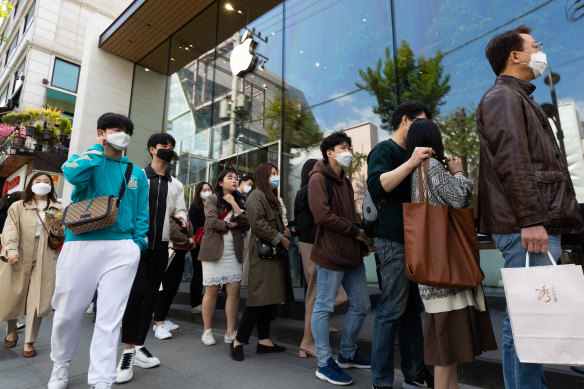 People wearing protective masks wait in line outside the Apple store in the Gangnam district of Seoul.