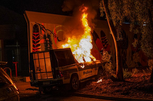 A police car burns outside Alice Springs Hospital during Thursday night’s unrest in the outback town.