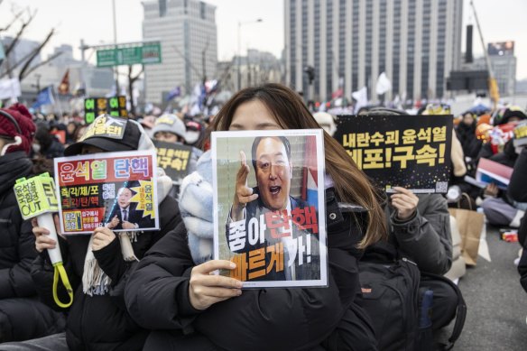 A demonstrator holds a placard featuring impeached South Korean President Yoon Suk Yeol.