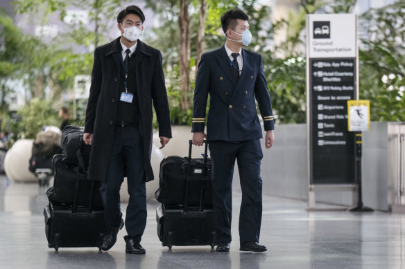 Air China flight attendants wearing disposable face masks walk through the departure hall at San Francisco International Airport in San Francisco as the US funnels flights through a selection of airports.