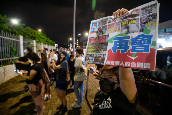 A supporter holds the latest newspaper outside the headquarters of the Apple Daily on Thursday. 