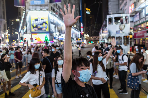 A demonstrator raises his hand as he blocks traffic on Hennessy Road during a protest in Causeway Bay. 