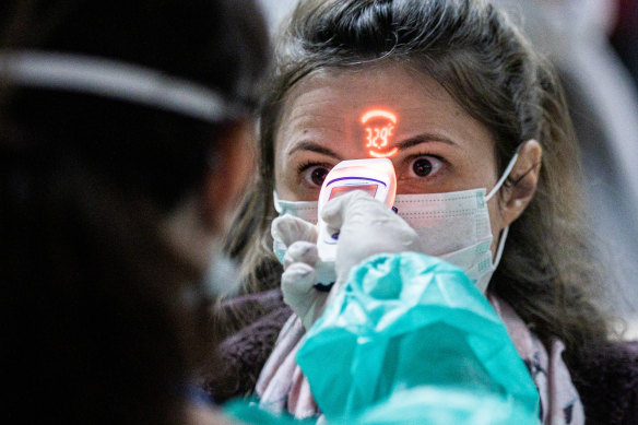 A health worker screens the temperature of an airline passenger arriving from Italy at Debrecen International Airport in Hungary.