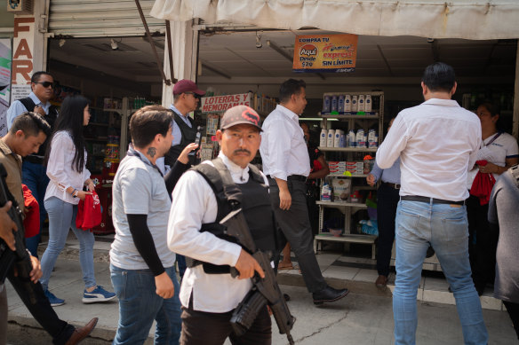 Security men accompany candidate Willy Ochoa as he gives a tour in the municipality of Las Rosas, Mexico.