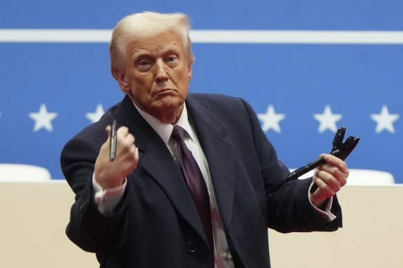 US President Donald Trump throws pens into the crowd after signing executive orders.