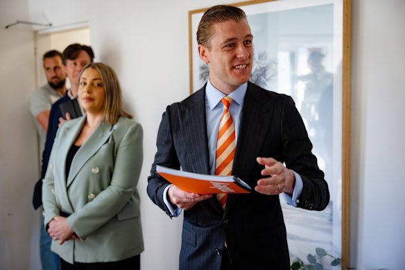 Auctioneer Jake Moore provides an acoustic distraction as potential buyers conferred between bids while Belle Property Randwick sales agent Emilee Tayyara looks on.