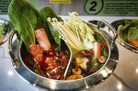 A duo base hot pot (with two broths) loaded with ingredients from the central conveyor belt.