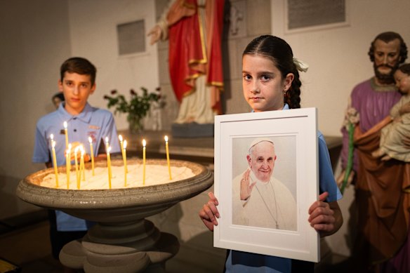 Saint Monica’s Primary School students Jenson Lambeth, 11, and Evie Bonnici, 11, light candles in Moonee Ponds, Melbourne, for Pope Francis.