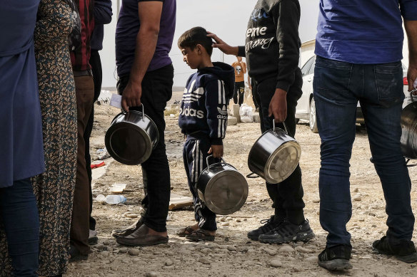 Syrian refugees fleeing the Turkish incursion in Northern Syria wait to receive water, bread and lentil soup as more than 200 arrive at the Bardarash IDP camp on October 17.
