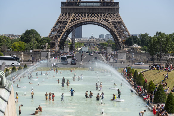 Parisians and tourists cool off in the Trocadero esplanade fountain near the Eiffel Tower in Paris.