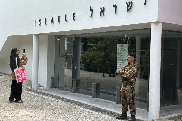 A woman takes a photo as an Italian soldier patrols the Israeli pavilion at the Biennale art fair in Venice on Tuesday.