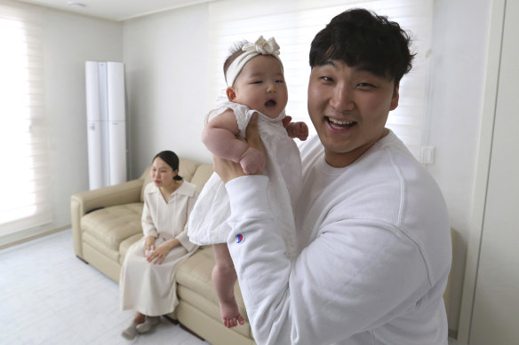 Lee Dong Kil holds his daughter Lee Yoon Seol with wife Ryu Da Gyeong on sofa. 