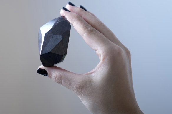 An employee of Sotheby’s Dubai presents a 555.55 carat black diamond “the Enigma”.