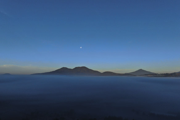 The moon rises over the pine-covered mountains surrounding the Indigenous township of Cheran, Michoacan state, Mexico.