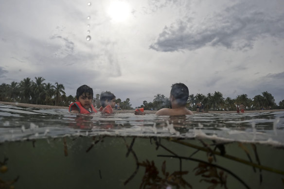 Galo Felipe Espinoza Sanchez, 5 (left), swims with his dad and cousin at Crandon Park beach, during the family’s visit to Florida from Ecuador and France on Friday.