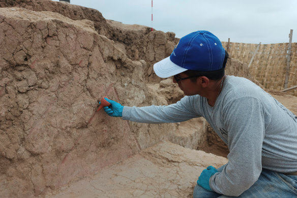 An archaeologist works on a 4500-year-old polychrome wall, part of a temple dated to the late Preceramic period, in the Huaca Tomabal in the Valley of Viru, Peru.