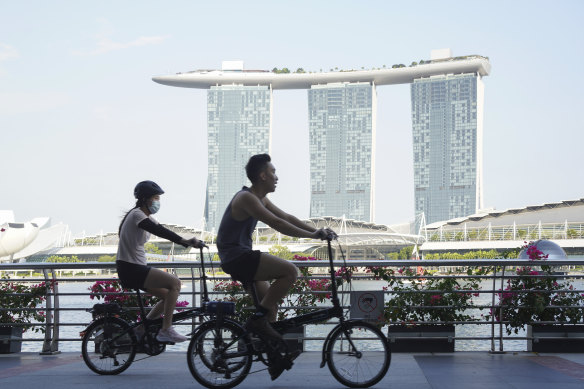 Cyclists ride past the Marina Bay Sands Hotel in Singapore, where curbs have been tightened this week.