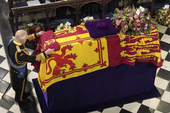King Charles III places the Queen’s Company Camp Colour of the Grenadier Guards on the coffin.