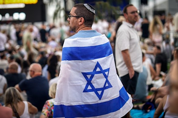 A man wearing an Israeli flag attends a memorial for the victims of the Bondi terror attack in Sydney.