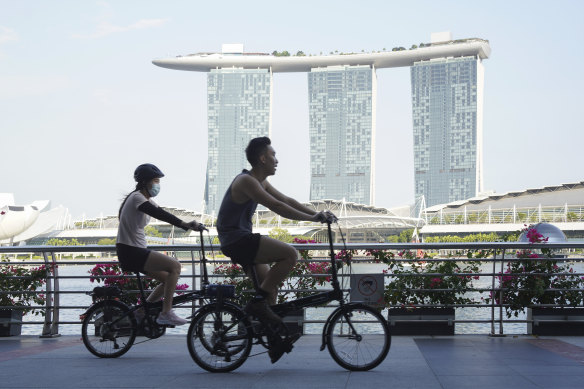 Cyclists ride past the Marina Bay Sands Hotel in Singapore, where curbs have been tightened this week.