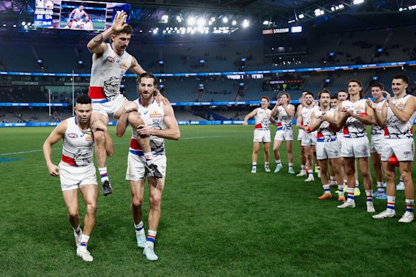 Tom Liberatore of the Bulldogs is chaired from the field after his 250th match by teammates Jason Johannisen (left) and Marcus Bontempelli.