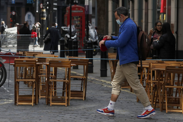 A man walks past empty restaurant tables in London. The UK has still not bounced back from the pandemic.