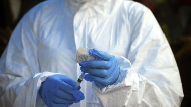 A health worker at the World Health Organization prepares to give a vaccine against Ebola.