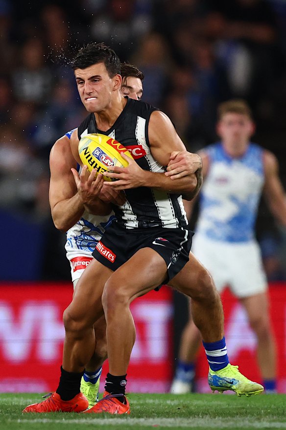 Jy Simpkin of the Kangaroos tackles Nick Daicos of the Magpies.