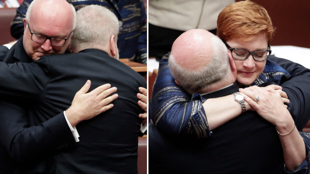 Senator Brandis is congratulated by Mitch Fifield and Marise Payne.