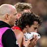 Andrew McGrath of the Bombers is helped from the ground by trainers.