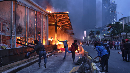 Rioters throw rocks at a burning bus station near the Welcome Monument in central Jakarta.